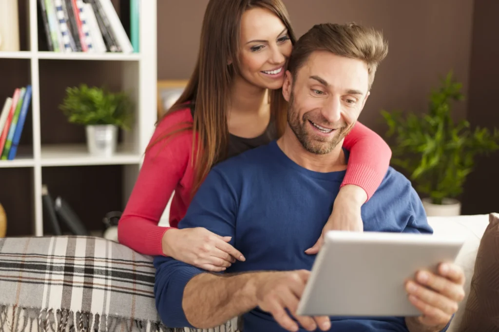 Smiling couple at home reviewing finances online